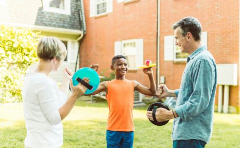 Un jeune garçon adopté, jouant allègrement dans le jardin avec ses nouveaux parents.