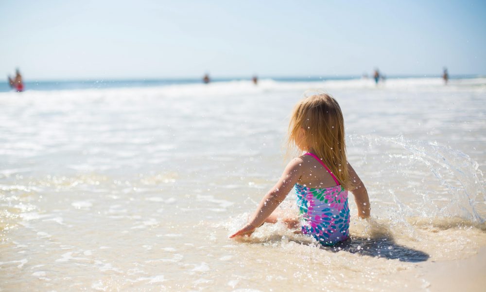 Une petite fille assise sur la page au bord de la mer