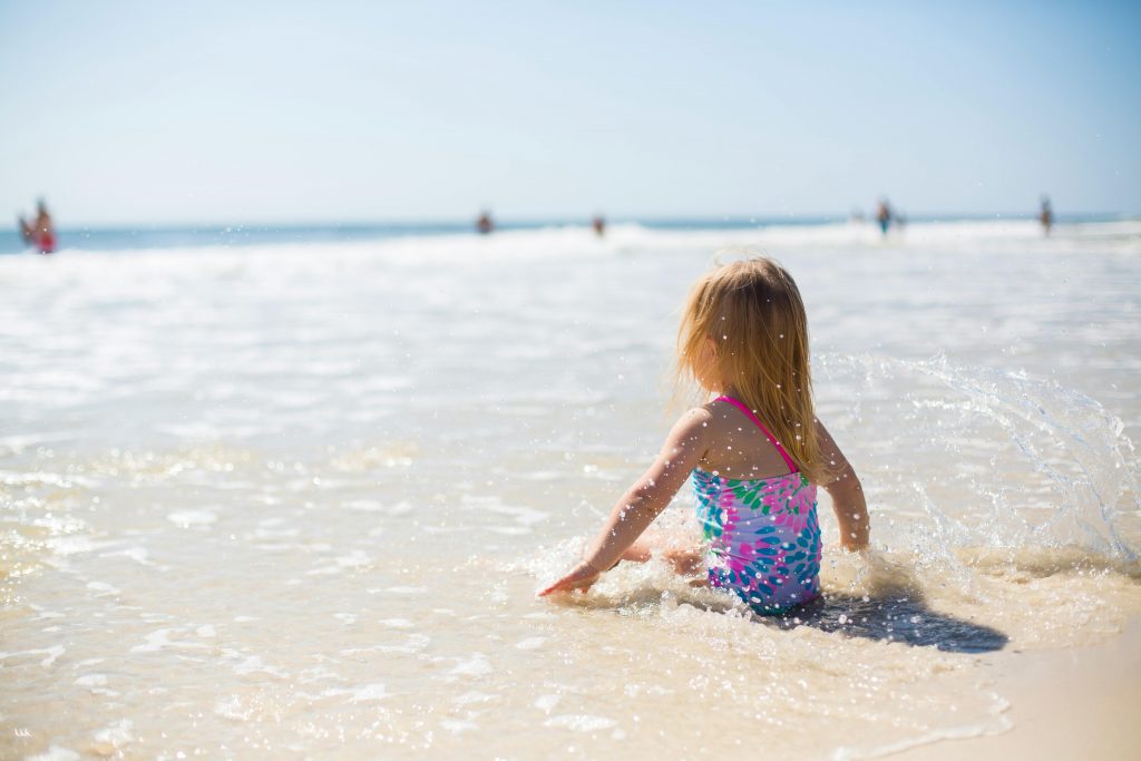 Une petite fille assise sur la page au bord de la mer