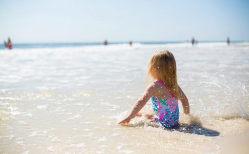 Une petite fille assise sur la page au bord de la mer