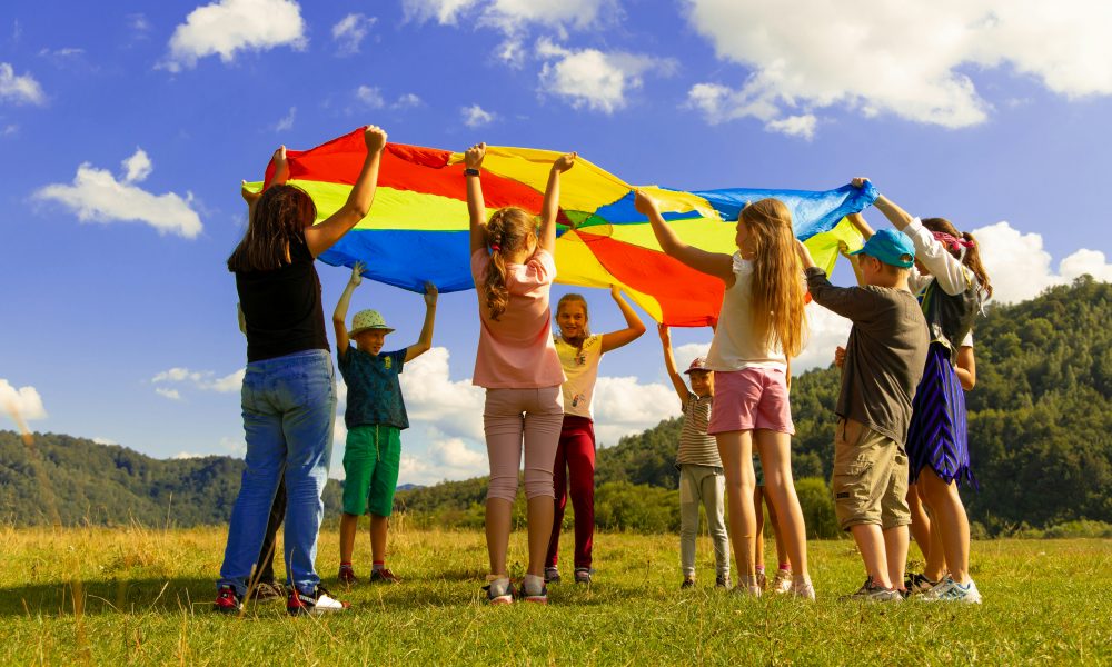 Des enfants jouant sous un grand drapeau dans un champ vert