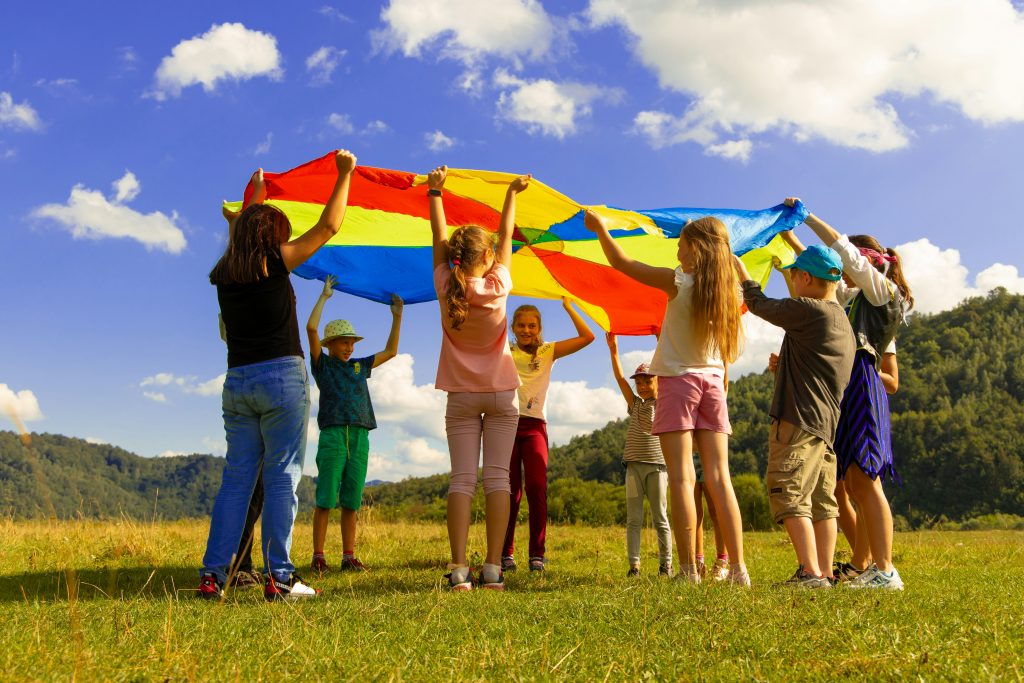 Des enfants jouant sous un grand drapeau dans un champ vert