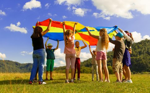 Des enfants jouant sous un grand drapeau dans un champ vert