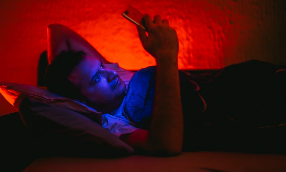 Un homme allonge dans le lit consultant son smartphone