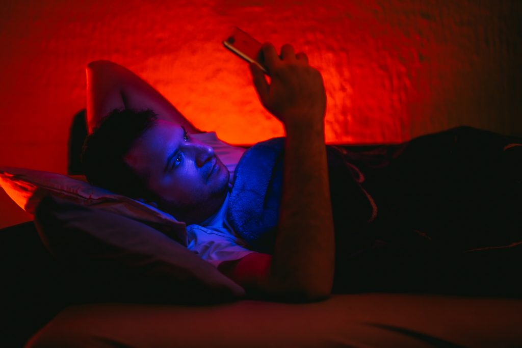 Un homme allonge dans le lit consultant son smartphone