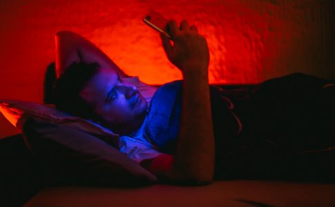 Un homme allonge dans le lit consultant son smartphone