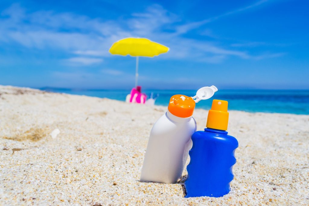 Deux flacons de creme solaire dans le sable sur la plage