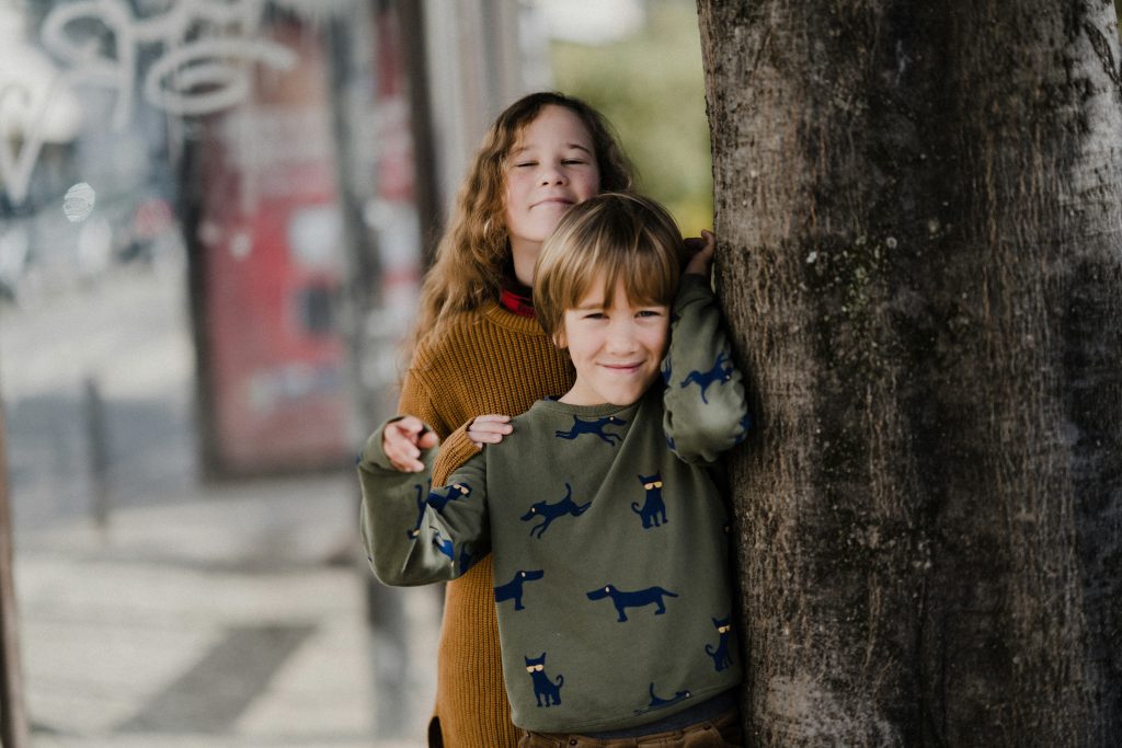 Une fille et un garcon se tenant pres d’un arbre