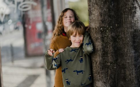 Une fille et un garcon se tenant pres d’un arbre