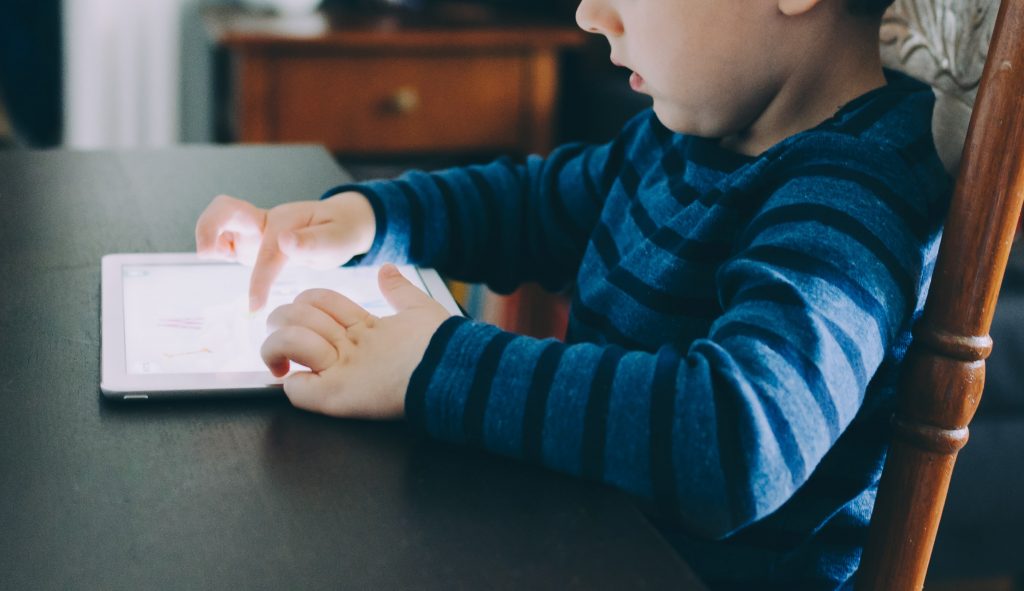 Une jeune garcon jouant a une tablette numerique