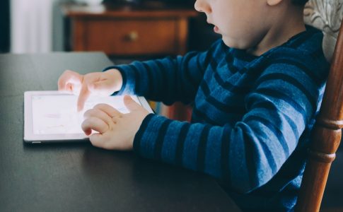 Une jeune garcon jouant a une tablette numerique