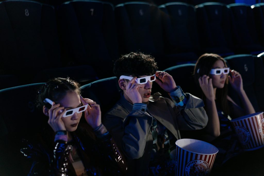 Trois jeunes au cinema portant des lunettes 3D