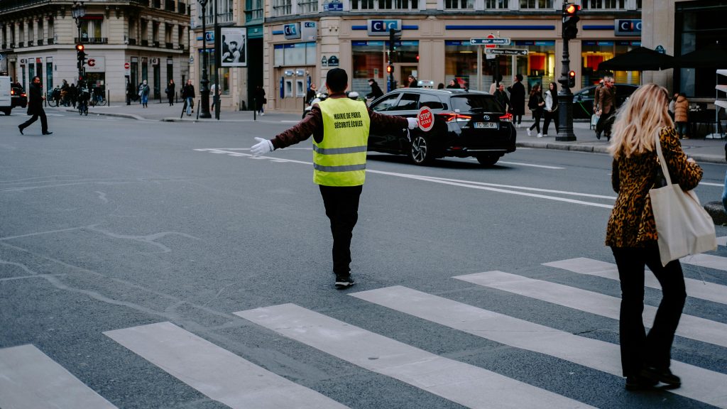 Un agent bloquant la circulation pour laisser des écoliers traverser, assurant une accessibilité de l’école pour tous.