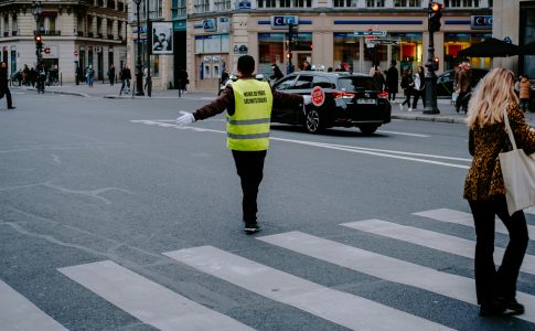 Un agent bloquant la circulation pour laisser des écoliers traverser, assurant une accessibilité de l’école pour tous.