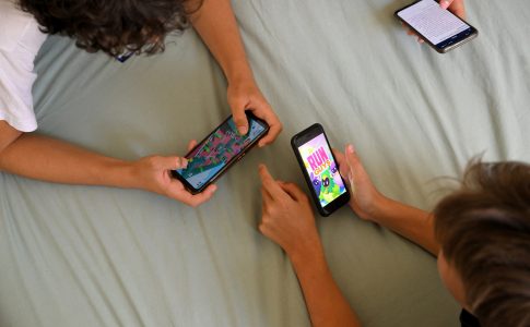 Deux ados en train de jouer a des jeux sur leur smartphone