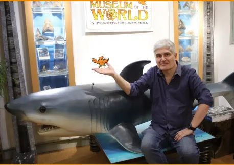 Homme devant représentation d’un requin avec petit oiseau orange dessinée dans la main 