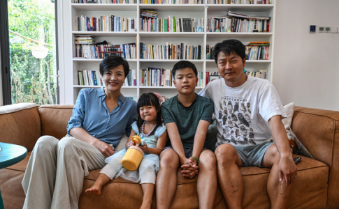 Une famille chinoise dans leur salon, avec un papa à plein temps et une maman working girl.