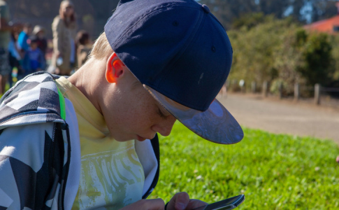 Un jeune garçon américain sur le chemin de l’école, en train de fixer son smartphone.