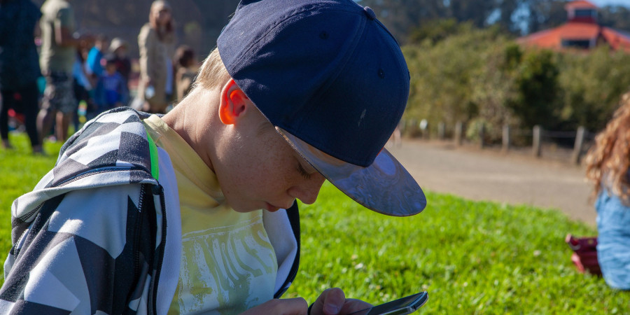 Un jeune garçon américain sur le chemin de l’école, en train de fixer son smartphone.