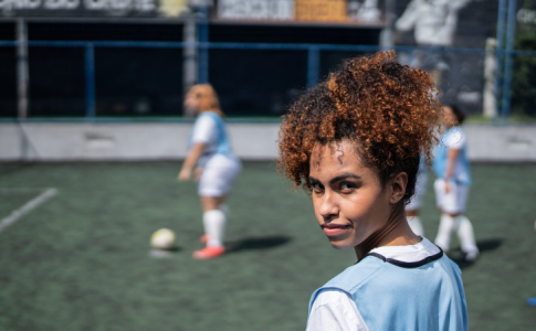 Une femme et son équipe de football sur le terrain en train de jouer.