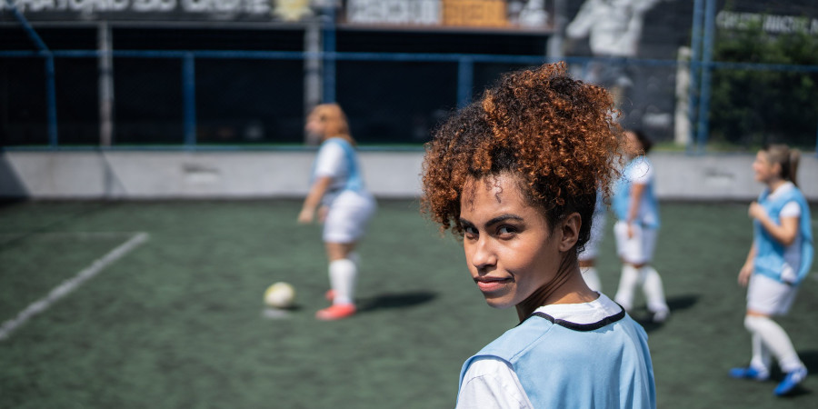 Une femme et son équipe de football sur le terrain en train de jouer.