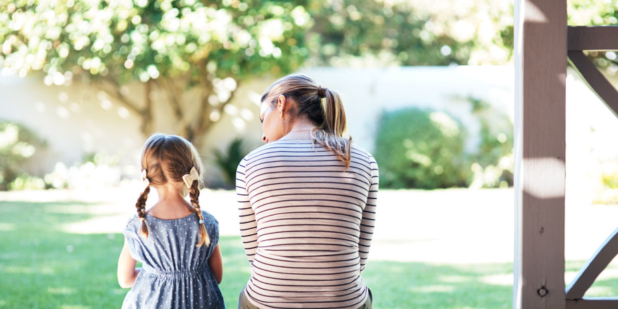 Une mère avec sa fille assises dans un jardin, en train de discuter.