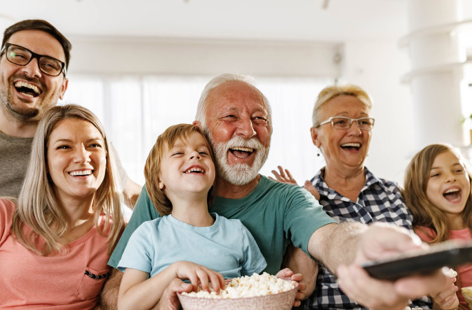 Une famille réunie dans leur salon, en train de regarder un film à la télévision.