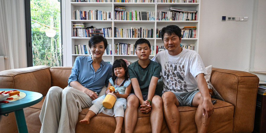 Une famille chinoise dans leur salon, avec un papa à plein temps et une maman working girl.