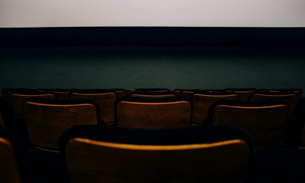 Rangée de chaises en bois dans une salle de cinéma.