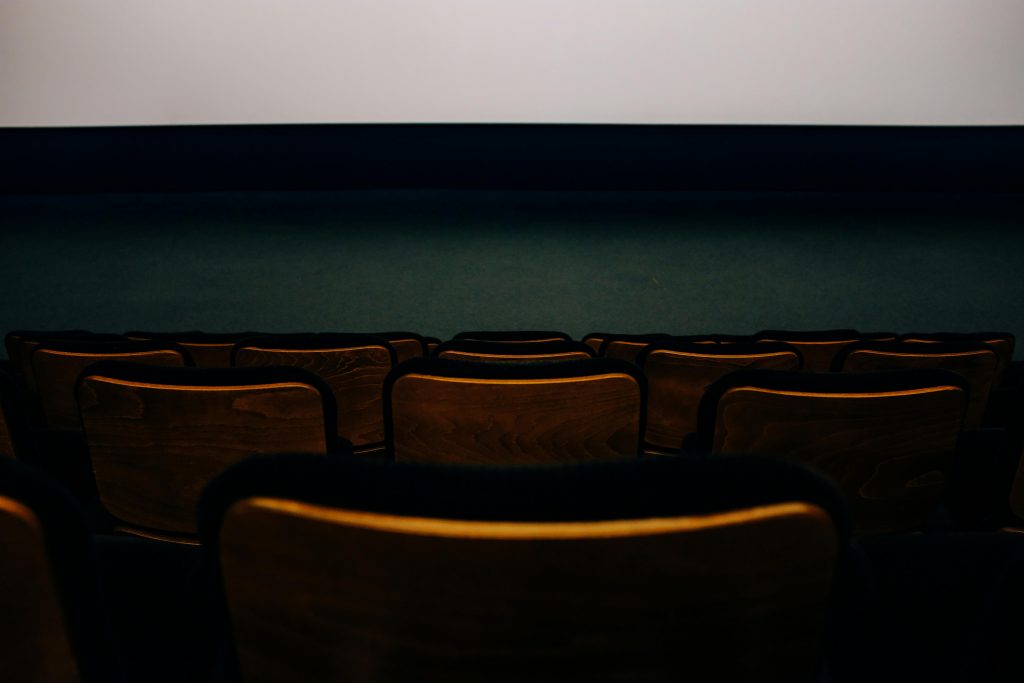 Rangée de chaises en bois dans une salle de cinéma.