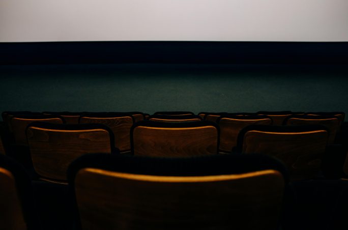 Rangée de chaises en bois dans une salle de cinéma.