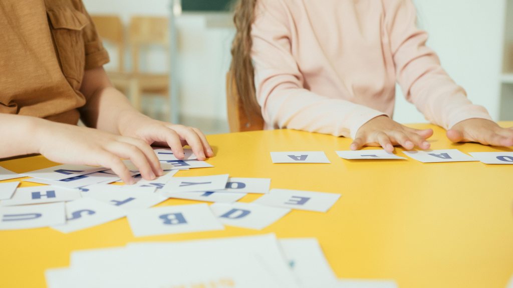 Des élèves allophones en train de former des mots français avec des carrés de lettres.