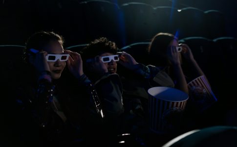 Trois jeunes en train de regarder un film au cinéma.