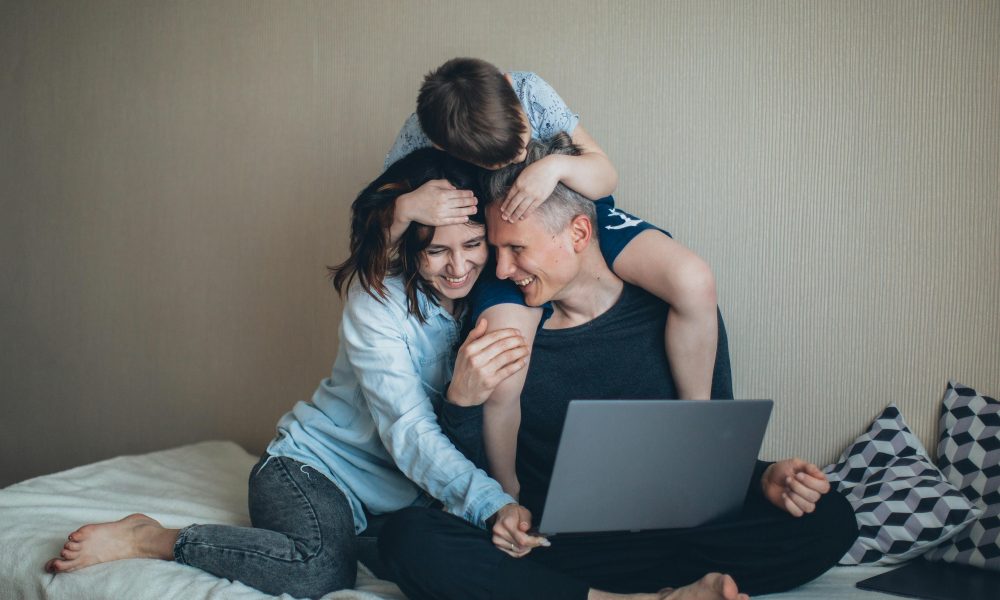 Une famille passant de bons moments à regarder un contenu sur PC, un facteur contribuant au bien-être des parents.