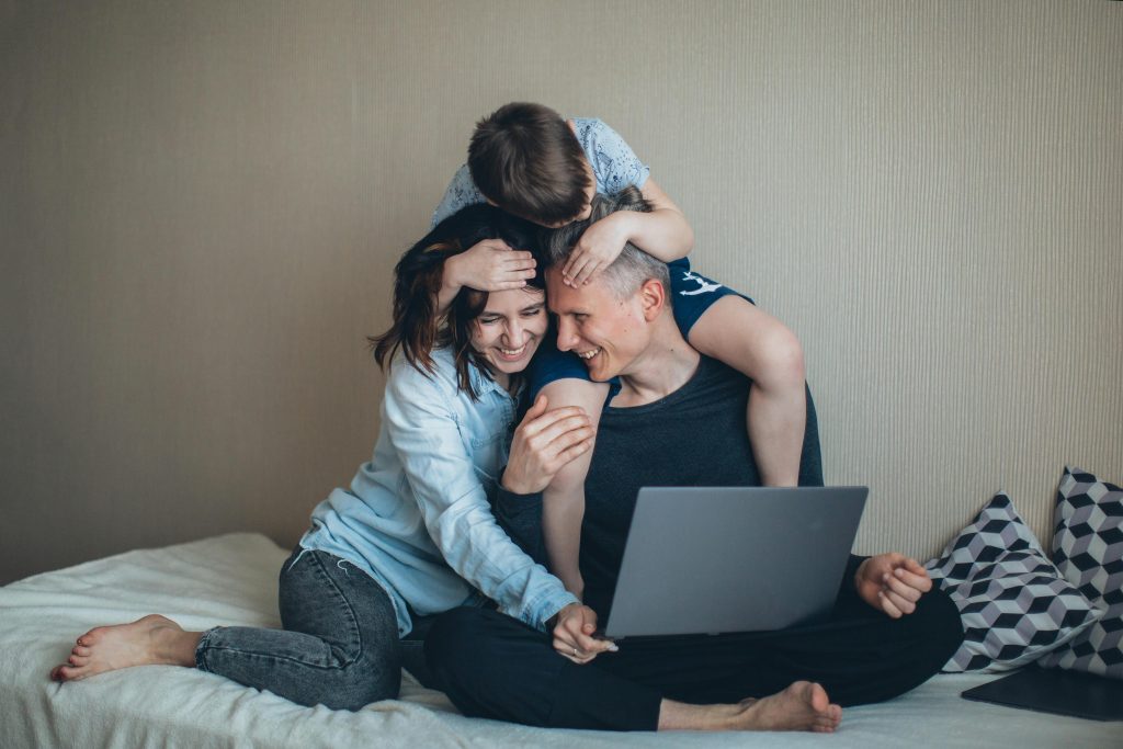 Une famille passant de bons moments à regarder un contenu sur PC, un facteur contribuant au bien-être des parents.