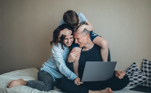 Une famille passant de bons moments à regarder un contenu sur PC, un facteur contribuant au bien-être des parents.