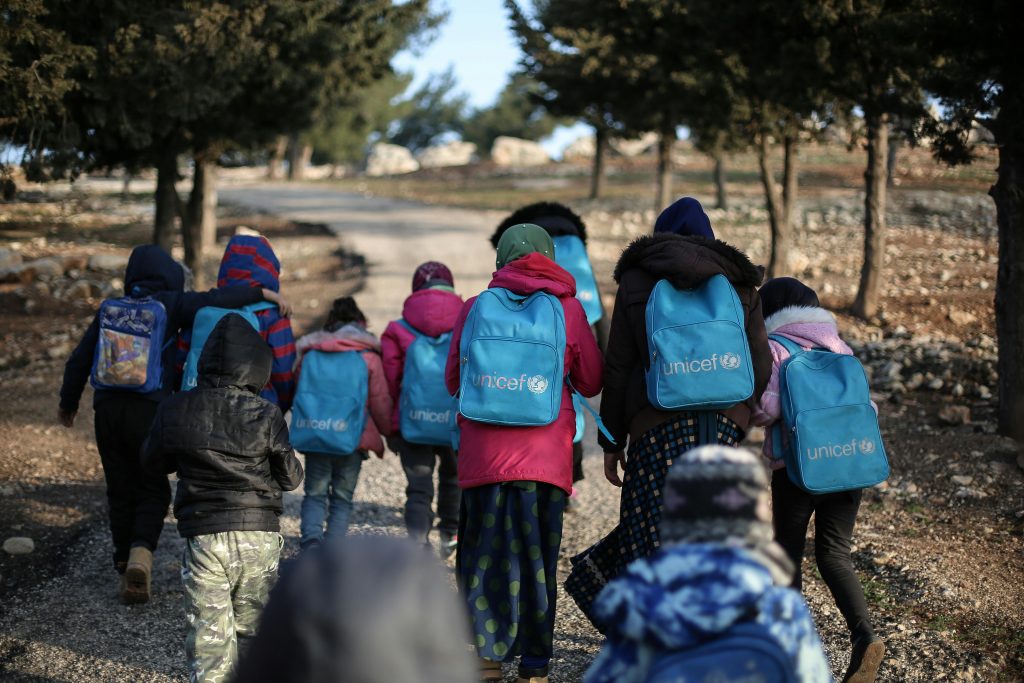 Des enfants marchant avec des sacs à dos UNICEF.