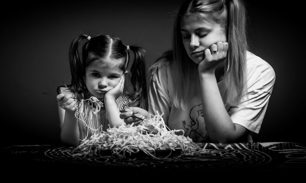 Des enfants difficiles rechignant à manger un plat de pâtes.