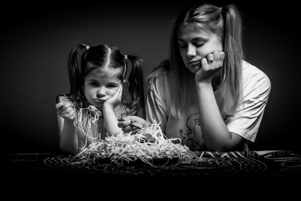 Des enfants difficiles rechignant à manger un plat de pâtes.