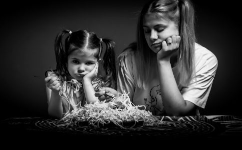 Des enfants difficiles rechignant à manger un plat de pâtes.