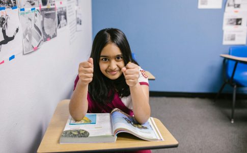 Jeune fille assise à son bureau, l'air sérieux, demandant qu’on l’écoute.