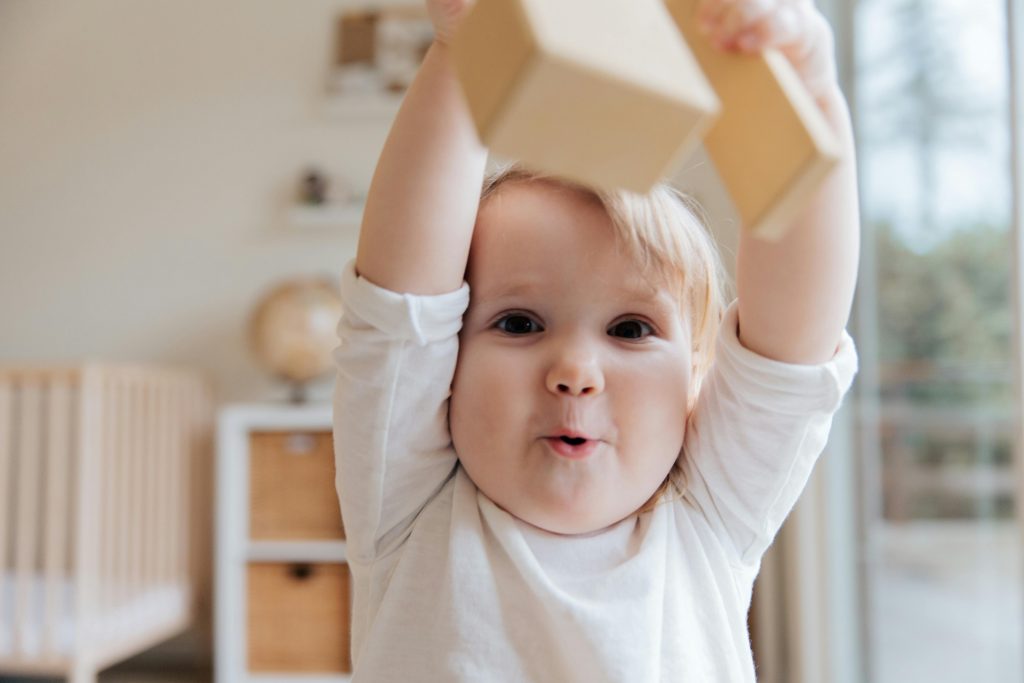 Bébé jouant avec des blocs en bois, dans sa chambre.