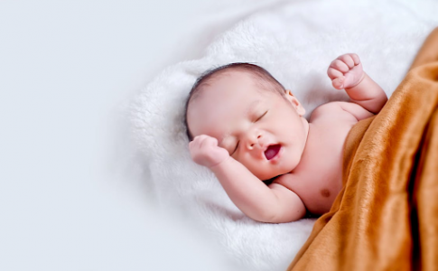 Bébé couché sur une fourrure blanche avec une couverture marron