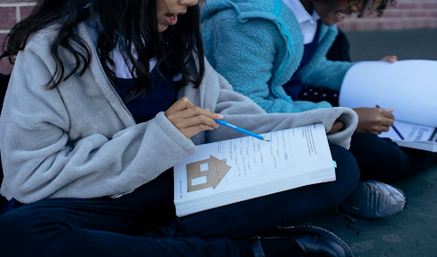 Jeunes élèves diversifiés qui étudient la leçon ensemble dans la cours