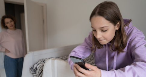 Des enfants utilisant des tablettes et smartphones surveillés par des parents attentifs.