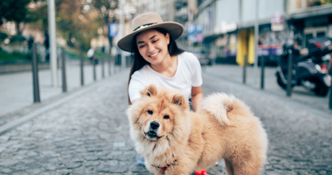 Une jeune femme en train de promener son chien dans la rue.