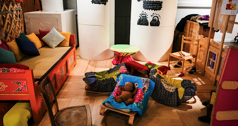 Grande pièce colorée avec des coussins et des espaces en bois à la Cité des bébés à Paris.