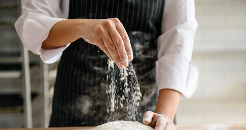 Un jeune cuisinier verse de la farine, représentant les débuts dans la création d’entreprise.