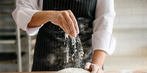 Un jeune cuisinier verse de la farine, représentant les débuts dans la création d’entreprise.