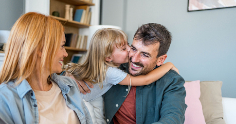 Une famille composée d’un père, d’une mère et de leur unique fille partageant un moment d’affection.